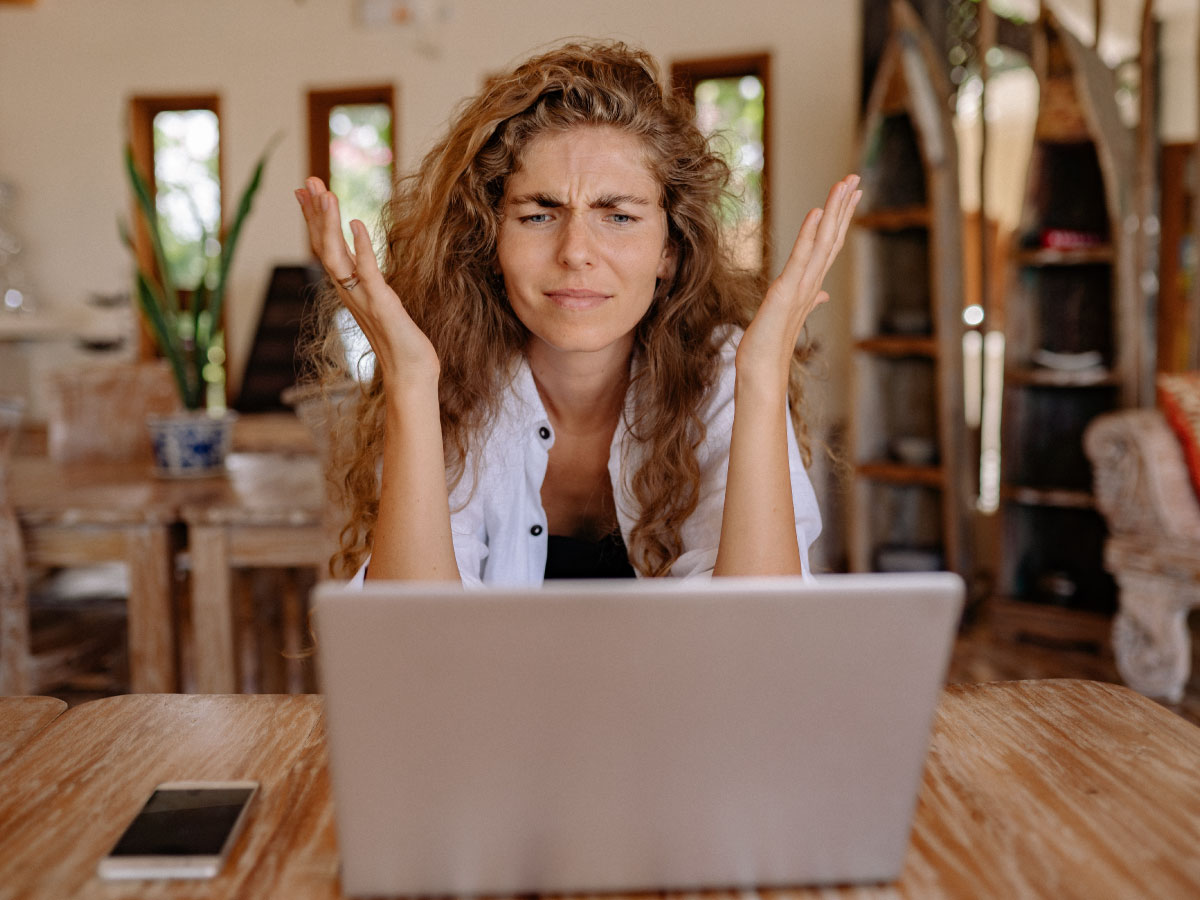 Woman looking at computer with confusion with hands up